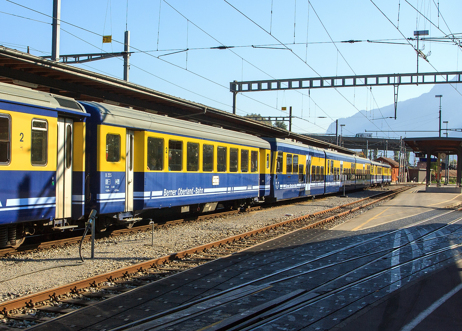 Eingereiht in einen BOB Pendelzug (Interlaken Ost – Grindelwald) am 02.10.2011 im Bahnhof Interlaken Ost, der BOB 2. Klasse Personenwagen B 255, ein Einheitswagen vom Typ SIG EW I bzw. Brünig Typ III (SIG1). 

Die SBB wählten für ihre schmalspurige Brünigbahn (heute Teil der Zentralbahn) nicht FFA, sondern SIG als Lieferantin der Einheitswagen. Deren Entwurf hielt sich äußerlich stärker an das normalspurige Vorbild, indem Plattform und Toilette außerhalb der Einstiege angesetzt wurden. Die Einstiegstüren wurden über den Drehgestellen angeordnet. Gemeinsam mit dem Entwurf der FFA war diesem Typ aber, dass der Sitzabstand offensichtlich vom Vorhandensein von „Schmalspurpassagieren“ ausging. Der Sitzteiler in der 2. Klasse ist mit 1.540 mm sogar noch geringer als beim FFA EW I ausgefallen. Da dies nicht ausreichte, wurden später bei der Modernisierung der Brünigbahn-Wagen zwei Sitzreihen weniger eingebaut, so dass der Sitzteiler (neu 1.760 mm) nicht mehr mit den Fenstern übereinstimmte. In der 1. Klasse wurden hingegen ein Sitzabstand von 2.055 mm geboten. Die Fenster wurden, wiederum gleich wie bei der Normalspur, für beide Wagenklassen mit 1.200 mm gewählt.

Der Beschaffung bei der SIG schlossen sich auch die BOB und die BVZ an. Die FO und die MOB, als einzige Adhäsionsbahn verzichteten auf eine Endplattform, was den Wagen ein eigenartiges unsymmetrisches Aussehen gab. Die MOB ließ darüber hinaus auch die Faltenbälge weg. Die vier Privatbahnen gönnten den erste Klasse Passagieren einen ungehinderten Blick auf das Bergpanorama durch 1400 mm breite Fenster, dafür wurde der Sitzabstand im A auf 1.932,5 mm und im AB auf 1.917,5 mm reduziert, was die Proportionen doch sichtlich veränderte. Der Erstklasswagen wurde bei gleicher Platzzahl wie am Brünig um einiges kürzer.

Auf Grund der unterschiedlichen Kupplungssysteme ist die Länge über Puffer ein ungeeignetes Vergleichskriterium. Die Kastenlänge beträgt bei allen Brünigbahn Wagen sowie bei den B für BOB und BVZ 17.3 m. Der A von BOB und BVZ wurde dagegen nur 16,485 m lang. Die reduzierte Abteillänge erlaubte es dafür beim Bau von AB, vier erste Klasse Abteile und drei zweite Klasse Abteile unterzubringen, anstatt der umgekehrten Zahlen beim AB für die Brünigbahn.

Da der Wagen für den Einsatz auf Zahnradbahnen konzipiert ist, wurde möglichst gewichtssparend gebaut. Es gibt (außer früher bei den Brünig AB) nur ein WC. Der Kasten ist aus Aluminium. Allerdings wurde bei den ersten elf Wagen (Prototyp für den Brünig und die ersten zehn Wagen für die BOB) die Legierung Unidur gewählt. Diese hatte nicht die erforderliche Festigkeit, weshalb von den elf Wagen nur noch fünf in Betrieb gehalten werden konnten.

2015 wurden 16 überzählige Wagen der Zentralbahn (zb) nach Benin und Niger verkauft.

TECHNISCH DATEN:
Baujahre: 1966 bis1971
Spurweite: 1.000 mm
Länge über Puffer : 18.070 mm
Wagenkastenlänge: 17.300 mm
Drehzapfenabstand: 12.830 mm
Drehgestelle: SIG-66 mit Bremszahnrad
Eigengewicht: 13 t
Sitzplätze: 64 in der 2. Klasse
Zul. Höchstgeschwindigkeit: 80 km/h
Zugelassen für Netz der: Brünig, BOB und LSE

