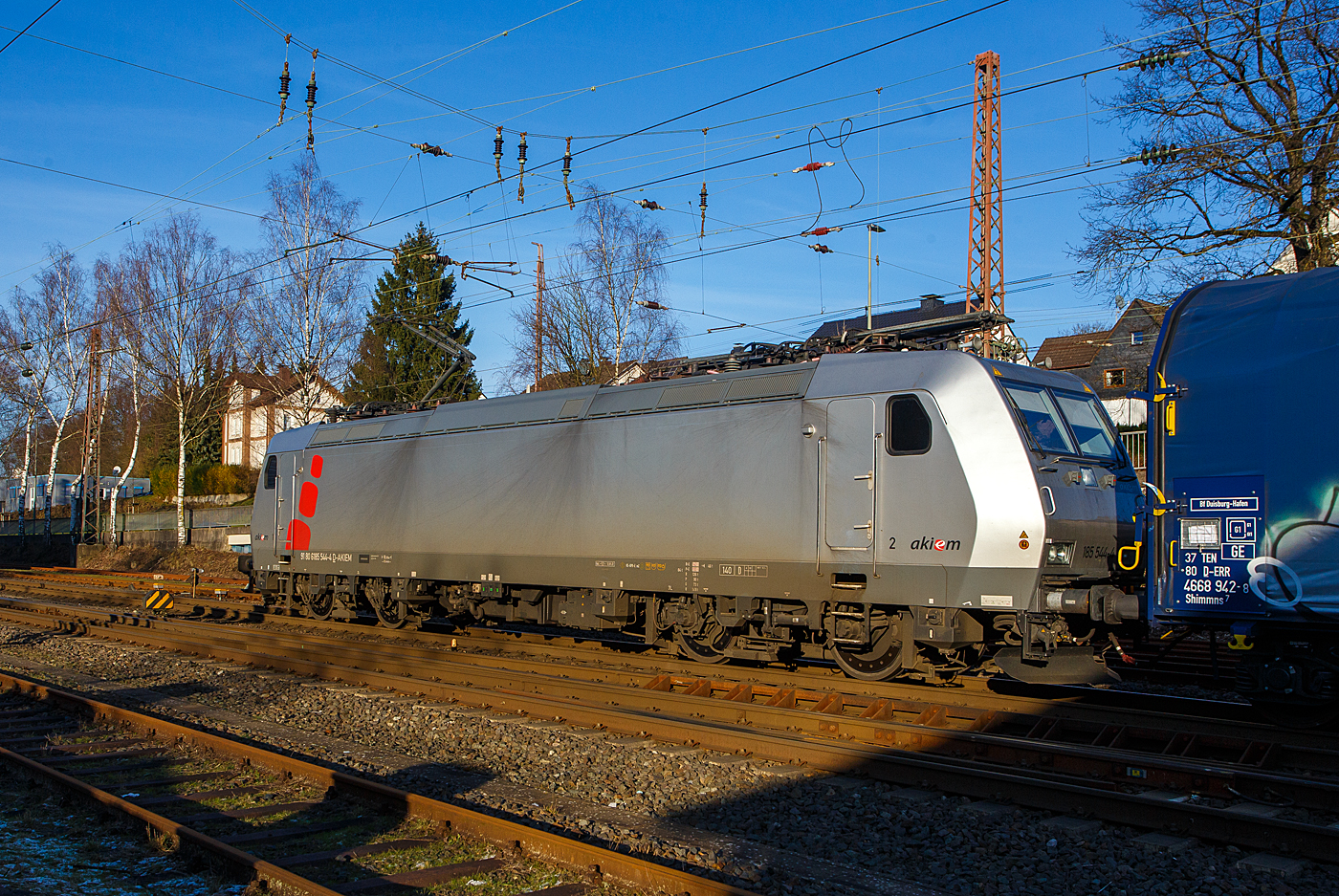 Heute am 8 Januar 2024 fegte ein bitter kalter Wind, aber endlich kam nochmal die Sonne hervor, so fuhren wir trotz der Bauerndemos nach Kreuztal, zudem ist ab morgen wegen dem GDL-Streik der Bahnverkehr lahm gelegt. Wir hatten den richtigen Weg gewählt und kamen zügig hin und zurück.

Die mit DACH-Zulassung (Deutschland, Österreich und Schweiz) an die DB Cargo AG vermietete Akiem 185 544-4 (91 80 6185 544-4 D-AKIEM), ex MRCE Dispolok (91 80 6185 544-4 D-DISPO), fährt mit einem Übergabezug (leere Coil-Wagen) vom Rbf Kreuztal in Richtung Hagen los. 

Die TRAXX F140 AC1 wurde 2005 von Bombardier Transportation GmbH in Kassel unter der Fabriknummer 33729 gebaut und an die MRCE - Mitsui Rail Capital Europe geliefert. An die AKIEM SAS wurde sie 2023 verkauft. Sie hat die Zulassungen für Deutschland, Österreich und die Schweiz (D/A/CH).
