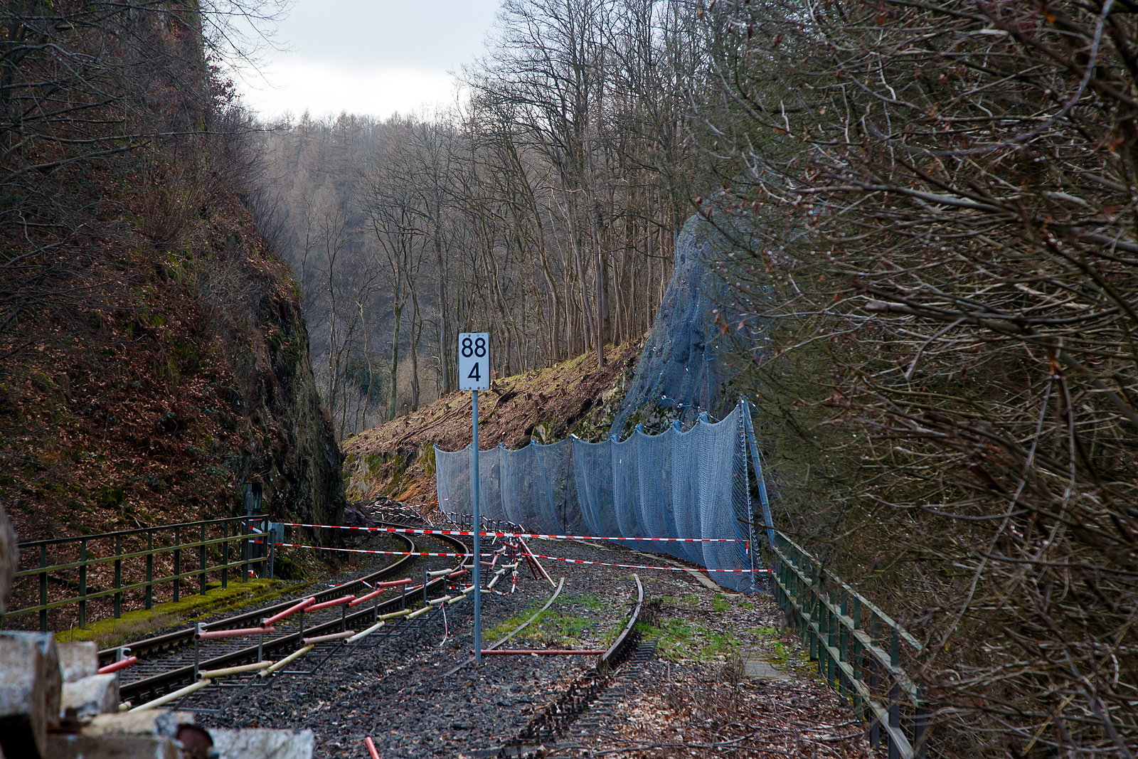 HLB Zug am 23.12.2022 auf der Hellertalbahn entgleist und die Strecke bleibt weiter, vermutlich bis Juni 2023 lange gesperrt...
Die Strecke der Hellertalbahn (KBS 462), vom Hp Königsstollen in Richtung Betzdorf gesehen am 04.02.2023. Hier sieht man Tatsache das rechts vom Gleis bereits umfangreiche Hangsicherungsmaßnahmen stattgefunden haben. Leider gab es am 23.12.2022 einen Erdrutsch (bei km 88,4) auf der linken Seite und ein Triebwagen entgleiste. Verletzt wurde zum Glück niemand.

Derzeit muss man von einer Sperrung der Hellertalbahn bis zum Juni ausgehen. Ja, die Sicherheit geht vor!!! Aber ist wirklich keine kurzfristige Maßnahme möglich. 

Neben der Sperrung der Bahn, gibt es in Herdorf wegen Straßenbauarbeiten schon genug Probleme mit dem Umleitungsverkehr auf den Straßen. Hinzu kommt ab Anfang April ein weiteres Problem in der Verbindung zwischen Betzdorf und Herdorf, denn dann wird der vom Landesbetrieb Mobilität beauftragte Abriss und Neubau der Hellerbrücke in Herdorf beginnen. Die L284 soll dafür bis August gesperrt bleiben und in den ersten sechs Wochen auch die wichtige Umleitungsverbindung über die L285 nach Daaden. 
