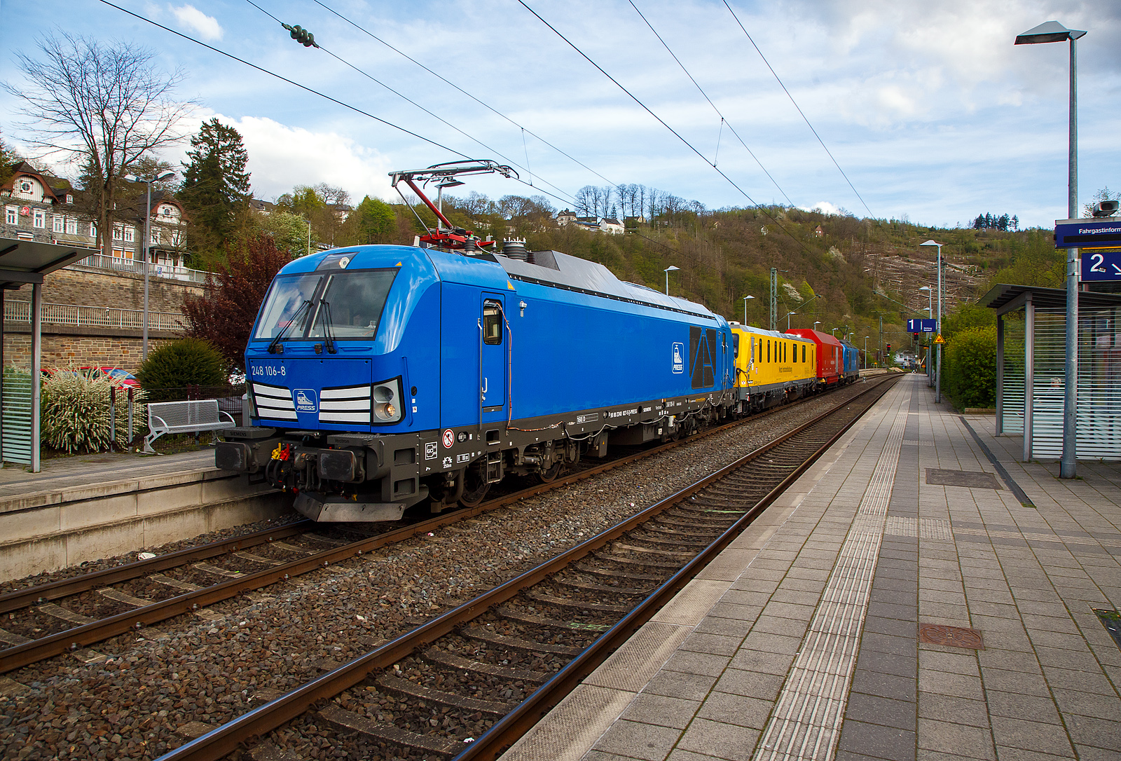 In einer ungewöhnlichen Komposition (im Sandwich zweier SIEMENS Vectron Dual Mode) fährt ein Schienenprüfzug (SPZ 3), auf Prüffahrt (der Messwagen ist auf die Schiene absenkt) am 30.04.2023 durch den Bahnhof Kirchen an der Sieg in Richtung Siegen. 

Die vierteilige Komposition bestand aus:
• Der SIEMENS Vectron Dual Mode der 248 027-5 (90 80 2248 027-5 D-PRESS) alias 248 106-8 der PRESS (Eisenbahnbau- und Betriebsgesellschaft Pressnitztalbahn mbH, Jöhstadt).
• Dem Messwagen SPZ-STW (STW steht für Steuerwagen) 720 301(99 80 9360 006-7 D-DB) der DB Netz AG (Netz Instandhaltung/Fahrwegmessung).
• Einem Hilfszug-Wagen (Nummer unbekannt) der DB Netz AG (Notfalltechnik).
• Und der SIEMENS Vectron Dual Mode der 248 026-7 (90 80 2248 026-7 D-PRESS) alias 248 105-9 der PRESS (Eisenbahnbau- und Betriebsgesellschaft Pressnitztalbahn mbH, Jöhstadt).

Die Energieversorgung vom Messwagen und dem Hilfszug-Wagen erfolgte von den Loks (spartanisch) über außenverlegte Kabel, zudem waren beide Loks über eine außenliegende Steuerleitung verbunden. Normalerweise ist der Schienenprüfzug ein zweiteiliger Messtriebwagen, bestehend aus Trieb- (ATW - 719 301) und einem Steuerwagen (STW - 720 301), siehe u.a. http://hellertal.startbilder.de/bild/Deutschland~Unternehmen~DB+Netz+AG/773623/der-plasser--theurer-schienenpruefzug-der.html Warum es nun diese Komposition ist, das ist mir nicht bekannt, vielleicht setzt man nun noch mehr auf E-antrieb.

Der Schienenprüfzug wurde 2015 von Plasser & Theurer in Linz (A) unter der Fabriknummer 6003 (SPZ-STW) gebaut. Um Schäden am Oberbau frühzeitig zu erkennen, setzt die Deutsche Bahn AG verschiedene Prüfzüge der Baureihen 719 und 720 ein. Mittels zweier zerstörungsfreier Prüfverfahren werden die Schienen auf Schädigungen untersucht. Bei der Ultraschallprüfung können Materialfehler durch Materialermüdung innerhalb der Schiene bis zum Schienenfuß erkannt werden. Mit der Wirbelstromprüfung wird der Schienenkopf geprüft.

Die beiden SIEMENS Vectron Dual Mode wurden 2022 von SIEMENS in München-Allach, unter den Fabriknummern 23168 und 23169, gebaut und an die PRESS - Eisenbahnbau- und Betriebsgesellschaft Pressnitztalbahn mbH in Jöhstadt geliefert. Die beiden Vectron DM haben die Zulassung in Deutschland für eine Höchstgeschwindigkeit 160 km/h.

Der Vectron Dual Mode vereint die Vorteile einer vollwertigen Diesellokomotive mit denen von elektrischen Lokomotiven. Dank des leistungsstarken Dieselantriebs sowie der Ausstattung für die Nutzung der Fahrleitung kann man jederzeit flexibel auf die Traktionsanforderungen reagieren. So bleibt man immer in Bewegung, egal ob mit oder ohne Fahrdraht. Wo ein Fahrdraht ist, sollte man ihn nutzen. Denn der Betrieb unter Oberleitung ist im Vergleich zum Dieselbetrieb deutlich kosteneffizienter und umweltfreundlicher. Doch weil es in Deutschland noch lange Zeit Strecken geben wird, die nicht vollständig elektrifiziert sind, fahren viele Diesellokomotiven unter Fahrdraht weiter. Das ist aber ökonomisch und ökologisch wenig sinnvoll. Dies ist hier ein Beispiel einer echten Alternative.