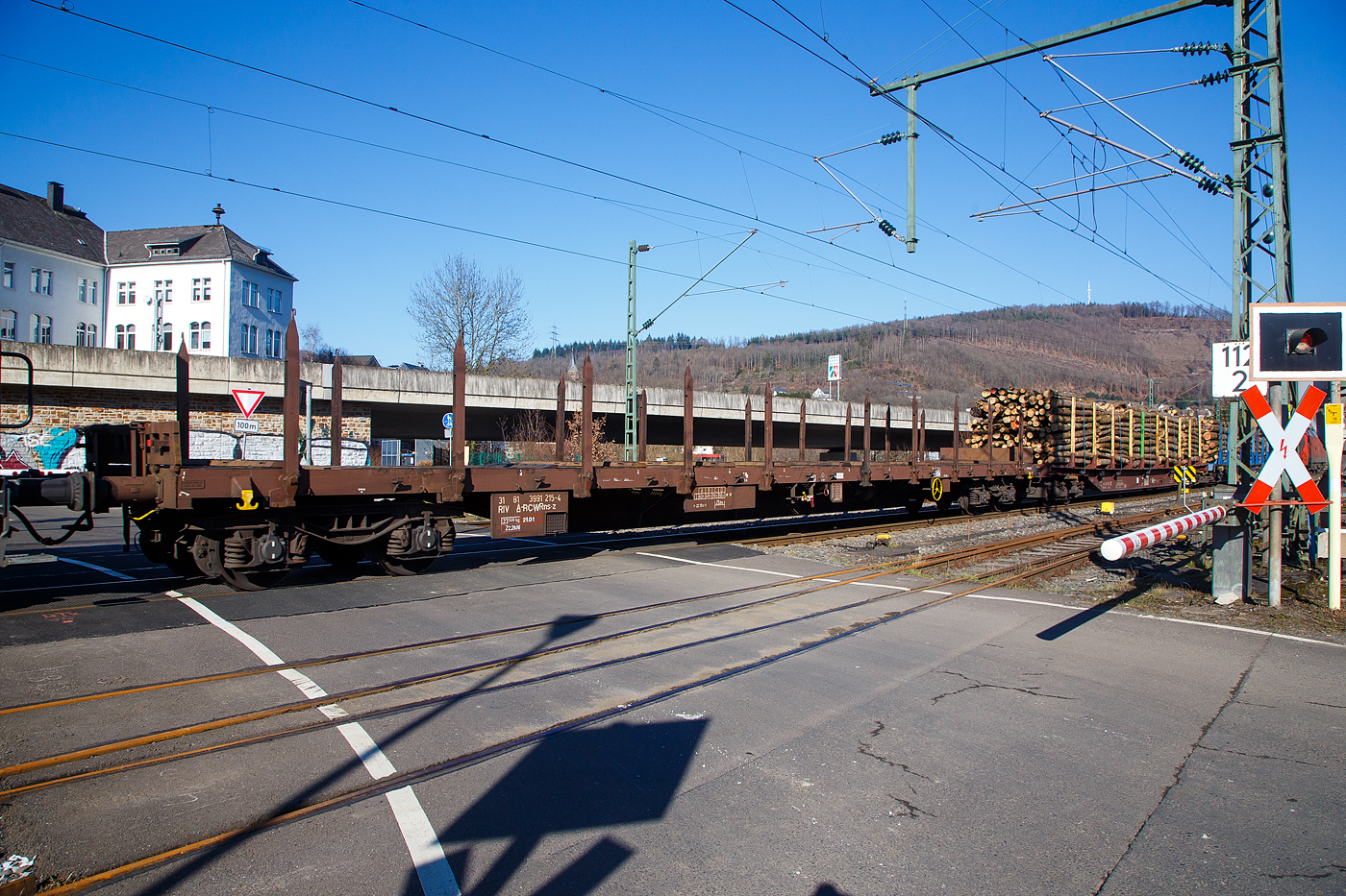 Leerer vierachsiger Drehgestell-Flachwagen, mit Stirnwandklappen und Drehrungen, ohne Seitenklappen, 31 81 3991 215-4 A-RCW, der Gattung Rns-z, der Rail Cargo Austria (zur ÖBB), im Zugverband am 14.02.2023 bei der Zugdurchfahrt in Niederschelden (Sieg).

Diese Wagen wurde Anfang der 1980er-Jahre von den Jenbacher Werke A.G.in Jenbach (Österreich) gebaut.

TECHNISCHE DATEN:
Spurweite: 1.435 mm (Normalspur)
Anzahl der Achsen: 4 (in 2 Drehgestellen)
Länge über Puffer: 22.350 mm
Drehzapfenabstand: 17.310 mm
Achsabstand im Drehgestell: 1.800 mm
Länge der Ladefläche: 21.000 mm
Höhe der Ladefläche von SOK: 1.260 mm
Rungenhöhe: 1.260 mm
Ladefläche: 55,4 m²
Eigengewicht: 23.500 kg
Max. Zuladung: 58,5 t (ab Streckenklasse C), 66,5 t (ab Streckenklasse C)
Max. Geschwindigkeit: 100 km/h (beladen) / 120 km/h (leer)
Bremse: O-GP-A (LL)
Bremssohle: IB 116
Feststellbremse: Ja
Kleinster Gleisbogenhalbmesser: 35 m
Verwendungsfähigkeit: RIV

Die Bedeutung der Gattungs- und Kennbuchstaben (hier Rns-z):
R - Drehgestellflachwagen in Regelbauart
n - höchste Lastgrenze über 60 t
s - lauffähig bis 100 km/h (beladen)
-z - Ladelänge 21 m
