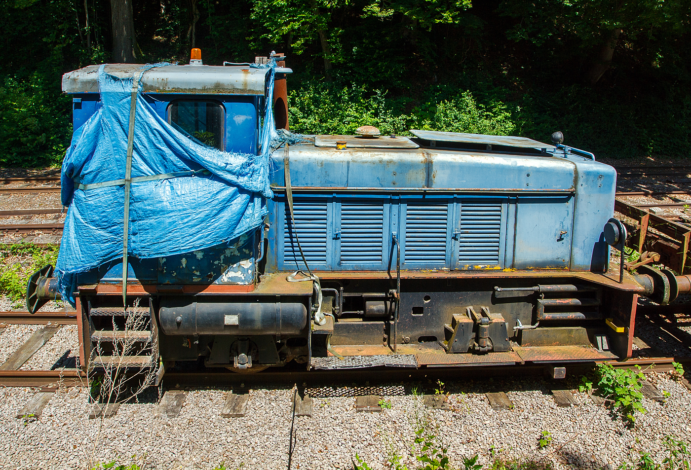 Leider schon in einem sehr schlechten Zustand pr�sentierte sich am 16 Juni 2013 die AMTF No 30, ex ARBED 130, ex ARBED 30, AES DH2, eine zweiachsige hydraulische Diesellokomotive vom Typ Jung RC 24 B (R = Regelspur, C = Antrieb �ber Gelenkwellen, 24 = 1/10 der Leistung in PS, B = 2 Achsen), bei der AMTF - Association des Mus�e et Tourisme Ferroviaires a.s.b.l. in Fond-de-Gras.

Die zweiachsige hydraulische Diesellokomotive wurde 1965 von der Arnold Jung Lokomotivfabrik GmbH in Jungenthal bei Kirchen an der Sieg unter der Fabriknummer 13870 gebaut und im Februar 1966 an die Eisenh�tte Arbed Esch-Schifflange AES als DH 2 geliefert. Hier lief sie oft mit ihrer Schwester, Kabine an Kabine, gekuppelt. Bei der Fusion der Lokbetriebe der ARBED (Aci�ries R�unies de Burbach-Eich-Dudelange SA, heute ArcelorMittal) erhielt sie erst die Bezeichnung ARBED 30, sp�ter ARBED 130. Einzeln lief sie dann auch in Belval bis sie �berz�hlig wurden. Nach langen Verhandlungen konnte die AMTF Ende der 1990er Jahre einen ihrer Finanzen entsprechenden Kaufpreis erreichen, und die Lok ging an die AMTF - Association des Mus�e et Tourisme Ferroviaires a.s.b.l. in Fond-de-Gras, wo sie die Nr. 30 bekam. Man musste aber einen Motordefekt feststellen. Zus�tzliche Kosten waren f�r die Austauschteile bei MTU (Mercedes) zu erwarten, doch Mechaniker vom TICE (Transport intercommunal de personnes dans le canton d'Esch-sur-Alzette) haben unentgeltlich gute Arbeit geleistet. Nachdem die meisten Beulen aus der Karosserie ausgebessert waren wurden sie blau gestrichen. Die Leistung der Lok gen�gte aber nicht um einen 3 Wagen Zug die Steigung von P�tange (Petingen) hochzuziehen.

Die Loks:
In den Nachkriegsprogrammen bot Jung ein zweiachsiges Muster f�r Industriebahnen mit unterschiedlichen Motorleistungen an. Die Fahrzeuge wiesen ein endst�ndiges F�hrerhaus und einen halbhohen, schmalen Motorvorbau auf. Die �u�ere Erscheinung des Musters blieb auch bei Umstellung von Ketten- auf Gelenkwellenantrieb weitgehend unver�ndert. Die gr��ten St�ckzahlen erreichten die Typen RK 15 B und RK 20 B (je 20 St�ck) sowie RC 24 B (26 St�ck).

Zur 4. Generation geh�rte die Jung RC 24 B (R = Regelspur, C = Antrieb �ber Gelenkwellen, 24 = 1/10 der Leistung in PS, B = 2 Achsen), eine zweiachsige hydraulische Diesellokomotive f�r den Rangier- und Verschubbetrieb, von denen 26 St�ck zwischen 1963-1976 von der Lokomotivfabrik Jung gebaut wurden. 

Technik:
Die Lokomotiven besitzen einen einfachen Vorbau f�r die Maschinenanlage und einen dahintergelegenen F�hrerstand. Der Maschinenraum war zur Verbesserung der Streckensicht im vorderen Teil abgewinkelt. Der Vorbau hatte T�ren zur Wartung der Maschinenanlage. Im F�hrerhaus befindet sich der F�hrertisch in der Mitte der Vorderwand. Bedienelemente f�r Fahren und Bremsen sind auf beiden F�hrerhausseiten vorhanden. Die Lok besitzt einen Blechrahmen aus Blechwangen mit einer St�rke von 15 mm sowie einer Pufferbohle. Der gesamte Rahmen ist in Schwei�bauweise hergestellt. Das Laufwerk besteht aus zwei mit Blattfedern abgefederten Achsen mit Gleitlagern. Die Federn st�tzen sich oberhalb der Achslager ab. Der Achsstand betr�gt 2.500 mm.

Die Maschinenanlage bestand aus einem wassergek�hlten aufgeladenen 6-Zylinder-Viertakt-Reihendieselmotor vom Typ Daimler-Benz MB 846 A mit einer Leistung von 184 kW (250 PS). �ber das nachgeschaltete Getriebe (Str�mungswendegetriebe) vom Typ Voith RS 18 Z erfolgt die Kraft�bertragung hydraulisch �ber zwei Gelenkwellen auf die beiden Achsgetriebe. 

TECHNISCHE DATEN:
Gebaute Anzahl: 26
Spurweite: 1.435 mm (Normalspur)
Achsordnung: B (2 Achsen)
L�nge �ber Puffer: 6.840 mm
H�he: 3.600 mm
Breite: 2.970 mm
Radstand: 2.500 mm
Dienstgewicht: 30t
Max. Achslast: 15,0 t
Dieselmotor Typ: 6 Zyl. Daimler-Benz MB 846A, 
Motorleistung: 184 kW (250 PS) bei 1.500 U/min
Getriebe: Voith RS 18 Z
Kraft�bertragung: dieselhydraulisch �ber Gelenkwellen auf die Achsen
H�chstgeschwindigkeit: 20 km/h
Kleinster befahrbarer Radius: 35 m
