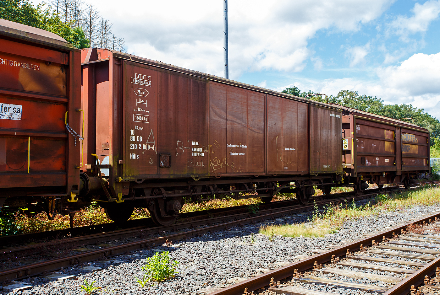 Privater gedeckter Güterwagen mit Schiebewänden der Gattung Hills, 10 80 2102 000-4, WEBA 02 (10 80 DB 210 2 000-4), der Westerwaldbahn (WEBA) abgestellt am 07 Juli 2024 auf dem Betriebshof der WEBA) auf der Bindweide bei Steinebach/Sieg abgestellt.

Der Wagen wurde 1989 von Rolanfer Matériel Ferroviaire SAS in Metz-Woippy (Frankreich) unter der Fabriknummer 534015 für die belgische SNCB gebaut, wann er auf den Westerwald kam ist mir unbekannt.

Beschreibung:
Der Wagen hat auf jeder Längsseite vier Schiebewände, so ist es möglich jeweils eine halbe Längsseide zu öffnen. Eingesetzt wurden diese Waggons für den Transport von großen nässeempfindlichen Stückgütern (bei dem Wagen waren es Büromöbel).

TECHNISCHE DATEN:
Spurweite: 1.435 mm
Länge über Puffer :12.540 mm
Achsabstand: 8.000 mm
Eigengewicht: 15.460 kg
Ladelänge:11.300 mm
Ladefläche: 28,7 m²
Rauminhalt: 64,6 m³
Höchstgeschwindigkeit: 100 km/h
Maximales Ladegewicht: 18,5 t (Streckenklasse C oder höher)
Bremse: KE-GP

Bei der WEBA war der Wagen nur auf der DB Strecke Scheuerfeld (Sieg) – Betzdorf (Sieg) zugelassen. Die WEBA hat 2017 den Güterverkehr eingestellt. Zudem ist für den Kunden der Bahntransport von Büromöbel (von Weitefeld nach Betzdorf) nicht mehr nötig.