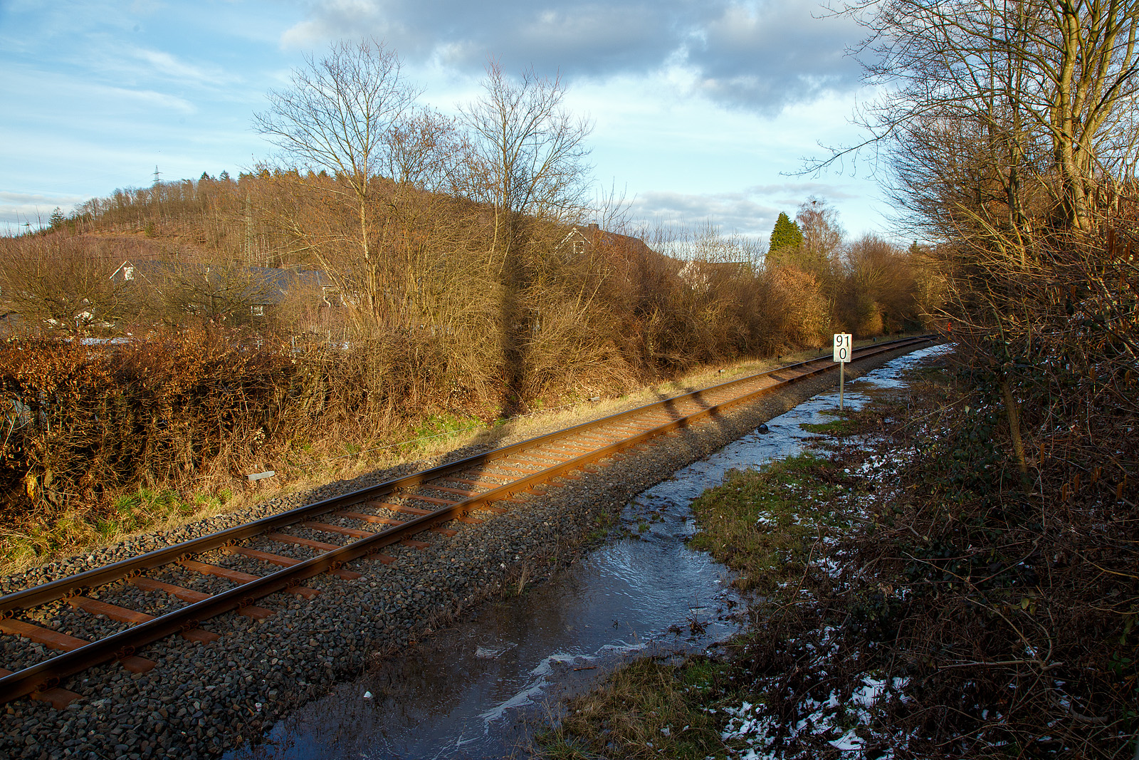 Schlimmer geht immer.....
Totalsperrung der Hellertalbahn (KBS 462 / Strecke 2651)
Nun ist Herdorf Bahntechnisch zur Insel geworden. 
Es gibt seit dem 10.03.23 eine Gleisunterspülung auf der Strecke 2651 bei km 91,0, so ist vorerst auch kein Güterverkehr von Haiger nach Herdorf möglich. Da die Strecke Betzdorf – Herdorf, bereits wegen dem Felsstutz  am 23.12.2022, seitdem gesperrt ist Herdorf nun Bahntechnisch ganz abgeschnitten. 

Eigentlich hatte ich am Mittag (11.03.2023) gedacht das Wasser fließt nun einfach ab. Aber leider war es am Nachmittag noch nicht so, der Wasserstand ist leider nur etwas gesunken.

Hier stehe ich nun am Funkmast, von hinten wo der in Arbeiter mit orangen Arbeitsjacke steht, kommt das Wasser bis hier geflossen und sucht sich den Weg unter dem Gleisbett hindurch auf die andere Seite.