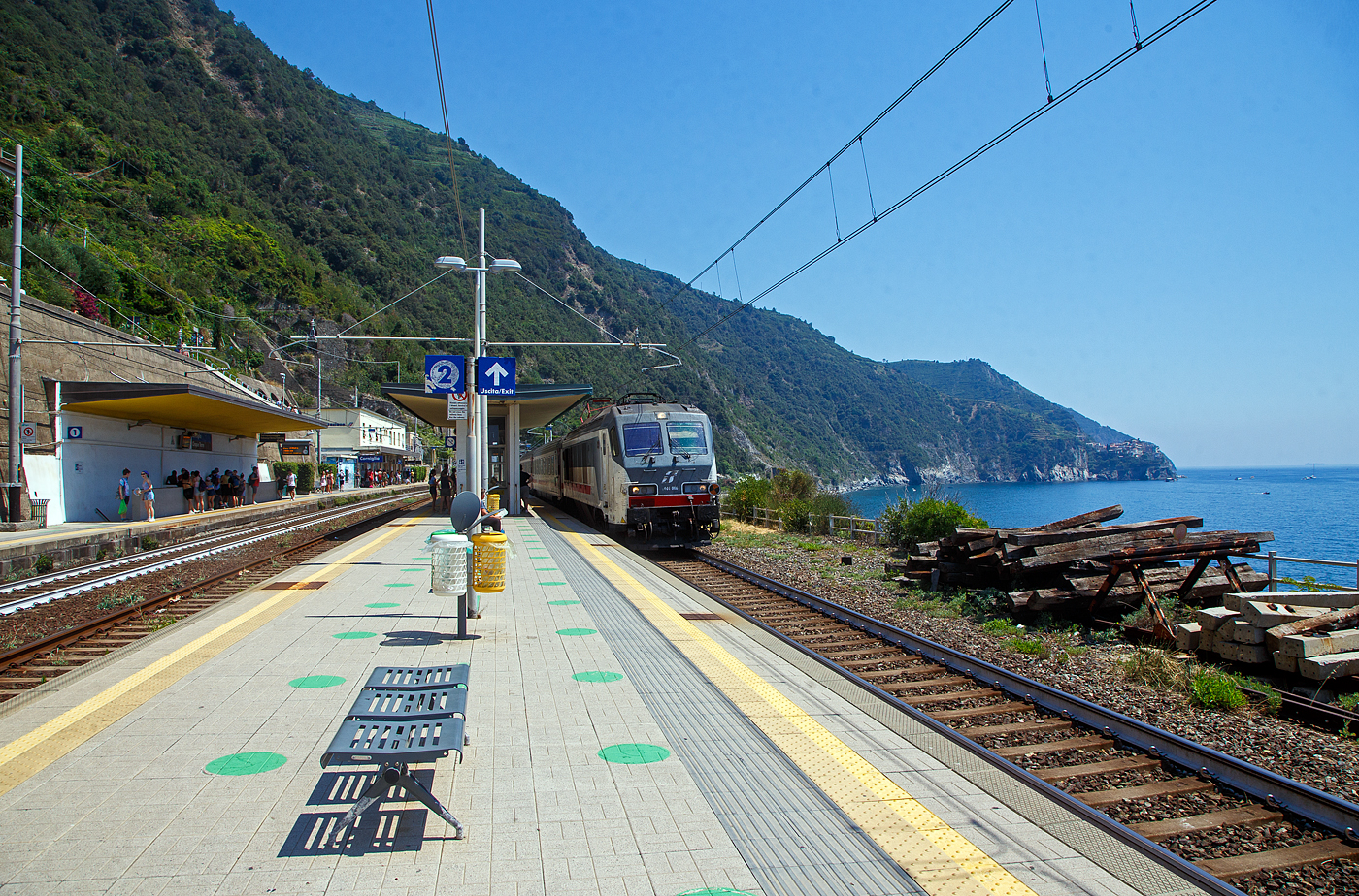 Trenitalia E.401.006 (91 83 2401 006-x I-TI), ex FS E.402.006 (E.402A) rauscht am 21.07.2022 mit einem Intercity (IC) durch den Cinque Terre Bahnhof Corniglia in Richtung Levanto bzw. Genua (Genova). 

Corniglia hat zwar diesen Bahnhof an der Bahnstrecke Pisa–Genua, aber Corniglia ist das einzige Dorf der Cinque Terre (5 D�rfer) das nicht direkt am Meer, sondern auf einem Bergvorsprung in etwa 100 m H�he, umgeben von drei gro�en Weinbergfl�chen und einer steilen Klippe zum Meer. So m�sste man hier vom viel tiefer gelegenen Bahnhof aus �ber die Lardarina, eine lange Ziegelsteintreppe, laufen. 

Wer wie wir die Cinque Terre Card Treno (Zugkarte) hat, k�nnte sich aber auch mit den Minibusen des Cinque Terre Parks (im Preis der Cinque Terre Treno Card eingeschlossen) die �ber 1 km lange Strecke hinauf fahren lassen. Aber die Busse waren uns einfach zu voll. Mit der Karte hat man auch Zutritt zu den beiden geb�hrenpflichtigen Wanderwegen des Cinque Terre Parks.


Rechts auf den Felsvorsprung kann man Manarola erkennen.


