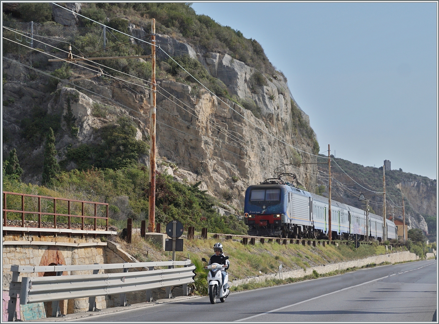 Typisch Italien, Bahn und Strasse teilen sich den engen Raum zwischen den aufragenden Bergen und dem Mittelmeer. Das Bild entstand bei Finale Ligure, und  gerade auf dem Streckenabschnitt an der Riviera dei Fiori verschwanden betr�chtliche Streckenabschnitte in Tunnel, so dass das die typische Italienische Bahnambiente schon fast die Ausnahme darstellt. 

Die FS Trenitalia E 464 509 ist mit einem Regionalzug auf dem Weg nach Ventimiglia. 

22. Sept. 2022