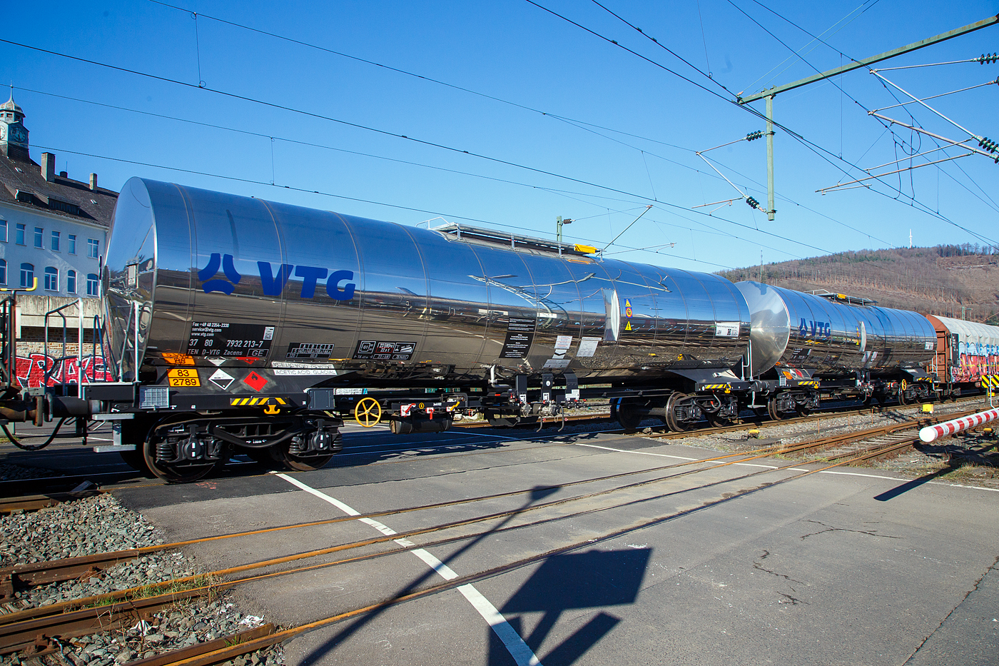 Vierachsiger 77 m³ Drehgestell-Kesselwagen mit Isolierung und Heizung, 37 80 7832 219-7 D-VTG der Gattung Zacens (VTG-Typ C52.077D), der VTG Rail Europe GmbH (Hamburg), im Zugverband am 14.02.2023 bei der Zugdurchfahrt in Niederschelden (Sieg). 
Die Gefahrguttafel (83/2789) zeigt es an: (oben) Gefahrgutnummer 83 = ätzender oder schwach ätzender Stoff, entzündbar (Flammpunkt von 23°C bis einschließlich 60°C) / (unten) UN-Nummer 2789 = ESSIGSÄURE mit mehr als 80 Masse-% Säure. Essigsäure ist eine farblose, flüssige, ätzende und typisch nach Essig riechende Carbonsäure. Als Lebensmittelzusatzstoff hat sie die Bezeichnung E260.

TECHNISCHE DATEN:
Gattung: Zacens
Spurweite: 1.435 mm
Länge über Puffer : 16.400 mm
Drehzapfenabstand: 11.360 mm
Achsabstand im Drehgestell: 1.800 mm
Höchstgeschwindigkeit: 100 km/h (120 km/h leer)
Kleinster befahrbarer Gleisbogen: R= 35 m
Eigengewicht: 23.290 kg
Nutzlast: 66,7 t (ab Streckenklasse D)
Gesamtvolumen: 76.940 Liter (ca. 77 m³)
Max. Betriebsdruck: 3 bar
Tankcode: L4BH
Behälterwerkstoff : Edelstahl
Heizung: 6-strängig, außen liegend, 8,4 m
Bauart der Bremse: KE – GP (K)
Bremssohle: Jurid 822
Handbremse: Ja, vom Boden bedienbar
Intern. Verwendungsfähigkeit: TEN-GE