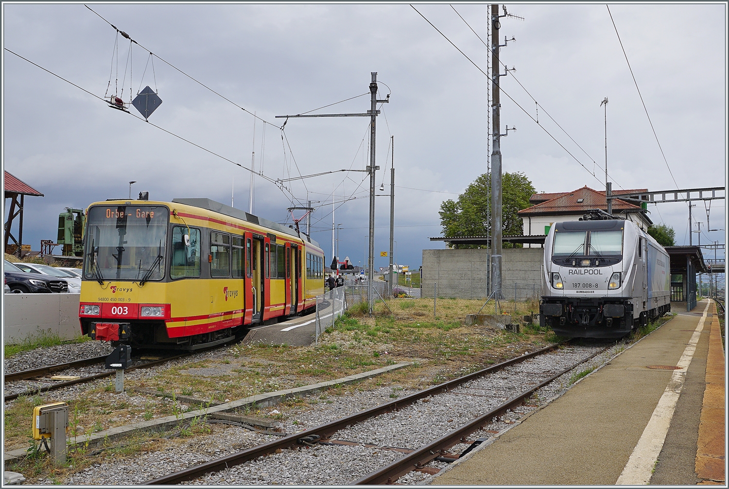 Zwei in Deutschland imatrikulierte Fahrzeuge stehen in Chavonray: Links wartet der TRAVYS/OC Be 4/8 003 auf die Abfahrt nach Orbe und rechts die an die BLS vermietete RailPool 187 008-8 auf ihre Güterlast. 

15. August 2022