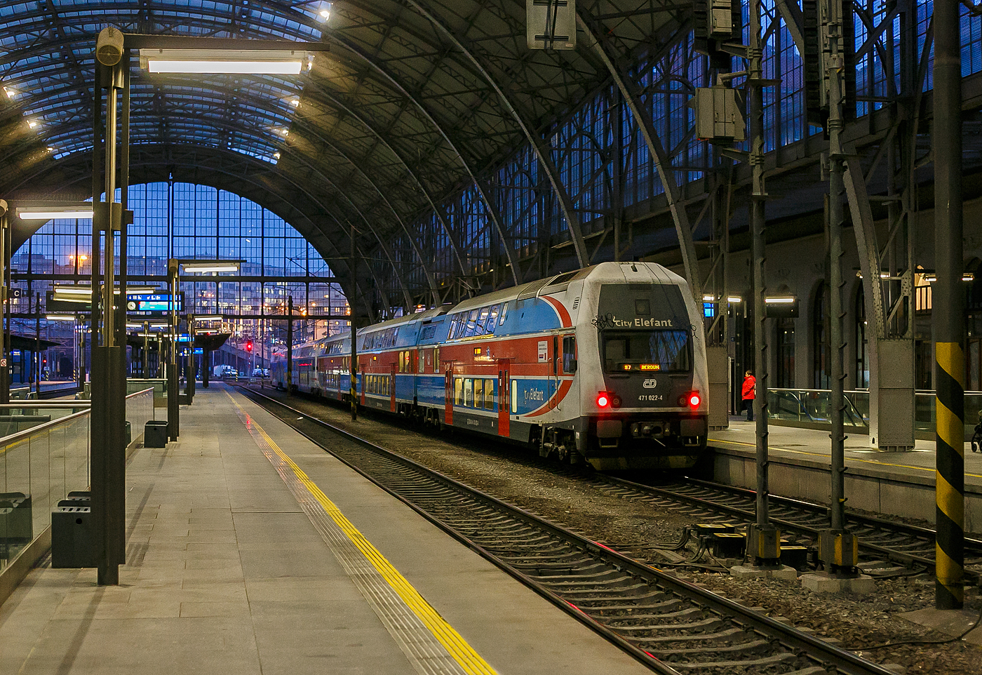 Zwei gekuppelte dreiteilige elektrische Doppelstocktriebz�ge vom Typ �koda CityElefant der ČD - Česk� dr�hy Baureihe 471 / 071 / 971, hier am Zugschluss der ET 471 022-2, verlassen am 22.11.2022, als S7 nach Beroun (deutsch Beraun), den Prager Hauptbahnhof (Praha hlavn� n�dra��).

Die dreiteiligen elektrischen Doppelstock-Triebz�ge der tschechischen Eisenbahn Česk� dr�hy (ČD) sind f�r den Regionalverkehr. Nach dem noch durch die ČSD 1988 eingef�hrten EDV-Nummernplan erhielten die Triebwagen die Baureihenbezeichnung 471, die Mittelwagen 071 und die Steuerwagen 971. Von den ČD werden sie als CityElefant vermarktet. Beschafft wurden die Fahrzeuge insbesondere als Ersatz f�r die �beralterte Baureihe 451/452. 

Geschichte:
Die Entwicklung begann 1992 durch die Hersteller MSV Stud�nka, sp�ter ČKD Vag�nka Stud�nka (mechanisch) und AEG (elektrisch), als man sich nach den negativen Erfahrungen mit der Baureihe 470 f�r eine Neukonstruktion entschied. Nach der Privatisierung von MSV Stud�nka war die AEG ab 1994 nicht mehr beteiligt, die Entwicklung der elektrischen Komponenten erfolgte durch �koda Verkehrstechnik. Die beiden Prototypz�ge der Baureihe wurden im Jahr 1997 von einem Konsortium aus den tschechischen Schienenfahrzeugherstellern Moravskoslezsk� vagonka und �koda Transportation fertiggestellt.

Mit ihnen wurden verschiedene neuartige Technologien im tschechischen Schienenfahrzeugbau eingef�hrt, so die Fertigung der Wagenk�sten aus stranggepressten Aluminiumprofilen, der Verwendung der Sandwichbauweise, IGBT gesteuerten Wechselrichtern mit Drehstrom-Asynchronmotoren sowie Klimaanlagen.

Von 2001 bis 2013 wurden die Serienfahrzeuge in Dienst gestellt. Nach anf�nglich gravierenden technischen Problemen wurde zum 5. August 2002 die Betriebserlaubnis zur�ckgezogen. Durch die mit dem Hochwasser 2002 einhergehende Ausnahmesituation in Prag wurde aber bereits zum 16. August 2002 wieder eine temp�rare Betriebserlaubnis erteilt. Diese galt dann bis zum 31. Oktober 2002, danach erfolgte durch die Hersteller die Beseitigung der M�ngel. Wegen finanzieller Probleme der ČD konnten nur etwa sechs Triebz�ge j�hrlich abgenommen werden.

2006 wurde die Produktion f�r ein Redesign unterbrochen, dieses wurde dann nach einem durch die ČD initiierten Wettbewerb unter dem Namen CityElefant vorgestellt.

TECHNISCHE DATEN:
Gebaute Anzahl: 83 (471 001 – 083)
Hersteller: �koda Vagonka Ostrava / �koda Transportation Plzeň
Baujahre: 1997 Prototyp / 2001 – 2013 Serienfahrzeuge
Spurweite: 1.435 mm (Normalspur)
Achsfolge: Bo’Bo’+2’2’+2’2’
L�nge �ber Puffer: 79.200 mm
H�he: 4.635 mm
Breite: 2.820 mm
Leergewicht: 158 t
Radsatzfahrmasse: 18 t
H�chstgeschwindigkeit: 40 km/h
Stundenleistung: 2.000 kW
Anfahrzugkraft: 180 kN
Stromsystem: 3 kV =
Anzahl der Fahrmotoren: 4
Bremse: Elektrische Bremse 1.700 kW
Sitzpl�tze: 310
Klassen: 1./2.
Kleinster befahrbarer Gleisbogen: R 120 m

Quellen: �koda und Wikipedia
