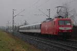 Am verregneten 12 Februar 2026 schiebt TRI 145 097 der RB 37 nach Krefeld Hbf durch Kaarst-Broicherseite und wird vom offenbarer Weg fotografiert. Dieser Himbeerroter Farbgebung ist eine kleiner Witz von TRI; die DB 145er haben diese Farben nie getragen.