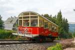 
Der Wagen 1 - Personenwagen der Standseilbahn der Oberwei�bacher Bergbahn befindet sich am 24.08.2013 auf Bergfahrt und erreicht gleich den Bergbahnhof Lichtenhain.
Der Personenwagen, im betrieblichen Umgang als Wagen 1 bezeichnet, ist seit der Er�ffnung 1923 nur an den Stirnseiten leicht ver�ndert worden. Das erfolgte 1959, als er gr��ere Stirnfenster erhielt und die leicht ausgestellte Stirnpartie. Bei der Rekonstruktion  2002 wurde die Fahrradb�hne angebaut. Besonderheit, sie ist nur am Fahrgestell befestigt und kann 8 Fahrr�der aufnehmen.

TECHNISCHE DATEN:
L�nge: 9,66 m (ohne Fahrradb�hne)
Breite: 3,93 m (ohne Tritte und Haltestangen)
H�he �ber SO: 4,08 m (variiert wegen Federung)
Eigengewicht: 26 t
Nutzlast: 7,5 t
Sitzpl�tze: 42
Stehpl�tze: 58

Bergbahntechnik einer ganz besonderen Art:
Die Bergbahn besteht aus zwei Teilen:
- der Standseilbahn, von Obstfelderschmiede nach Lichtenhain und
- der  Flachstrecke  der Bergbahn, von Lichtenhain nach Cursdorf
Die Konzession zum Bau wurde f�r eine Eisenbahnstrecke von Obstfelderschmiede nach Cursdorf erteilt, heute als Strecke Nr. 6691, KBS 563, der Deutschen Bahn AG gef�hrt. Die Standseilbahn ist also ein Bestandteil dieser Eisenbahnstrecke.
Die Standseilbahn hat zwei unterschiedliche Fahrzeuge, einen “Personenwagen” und eine “G�terb�hne” zum Transport normalspuriger Eisenbahnwagen bis 27 t Gesamtmasse.
Sie wurde gebaut f�r den G�terverkehr, um die Hochebene um Oberwei�bach an das deutsche Eisenbahn-Netz anzuschlie�en.
