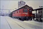 An einem trüben und schneereichen Märztag steht die SBB Ae 6/6 11416  Glarus  mit einem Postwagen in Beromünster auf Gleis 1.