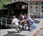 - 2007 in Gletsch - Die Fahrg�ste legen Hand an beim Drehen der Dampflok auf der Drehscheibe in Gletsch.