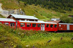 Der vierachsige Personenwagen A 4162, ex BVZ A 2062, ein Mitteleinstiegswagen der ersten Wagenklasse, abgestellt in Realp (Uri) von/bei der DFB Dampfbahn Furka-Bergstrecke AG am 07 September 2021, aufgenommen aus einem fahrenden MGB-Zug heraus.

Der Wagen wurde 1961 von SIG (Schweizerische Industrie-Gesellschaft) in Neuhausen am Rheinfall gebaut und an die damalige BVZ (Brig-Visp-Zermatt-Bahn / BVZ Zermatt-Bahn) als A 2062 geliefert. Nach dem Zusammenschuss am 01. Januar 2003 der BVZ mit der Furka-Oberalp-Bahn (FO) zur Matterhorn-Gotthard-Bahn wurde er zum MGB A 2062, im Jahr 2015 ging er dann an die DFB. Im Mai 2017 war er der erste reine 1. Klasse-Wagen im DFB-Rot.

TECHNISCHE DATEN
Hersteller: SIG
Baujahr: 1961
Spurweite: 1.000 mm (Meterspur)
Anzahl der Achsen 4 (2´2´)
L�nge �ber Puffer : 15.780 mm
L�nge des Wagenkastens: 14.900 mm
Breite: 2.656 mm
H�he: 3.365 mm
Drehzapfenabstand: 11.010 mm
Achsabstand im Drehgestell: 1.800 mm
Laufraddurchmesser: 675 mm
Bremszahnrad: System Abt  (Drehgestell Seite Visp/Talseite)
Eigengewicht:  11,8 t 
Ladegewicht:  3 t
Zul. H�chstgeschwindigkeit: 90 km/h
Anzahl der Fenster (1.400 mm breit): 6 (WC-Seite) bzw. 7
Sitzpl�tze: 34 und 2 Klappsitze
Stehpl�tze: 6
Lichte T�rbreite: 2 x 610 mm
Toiletten: 1
Heizung: Zugsammelschiene RhB/MGB
Bremsen: automatische Vakuum- und Handbremse
Zulassungen: MGB und RhB

Warum ist aus dem BVZ A 2062 nun der DFB A 4162 geworden?
Dies liegt an dem Nummernsystem der der Bahnwagen der DFB.

Die Wagenbezeichnungen setzen sich aus einem Typenschl�ssel bestehend aus Buchstaben und einer Nummer zusammen. Die Typenbezeichnung – z.B. das A aus A 2062 - ist genormt. Wenn ein Wagen von der DFB �bernommen wird, wird sie deswegen beibehalten, sofern die Art des Wagens gleich bleibt.
Nachstehend die wichtigsten Typenbezeichnungen:
A 1. Klasse-Wagen
B 2. Klasse-Wagen
C 3. Klasse-Wagen (offene Plattform)
D Gep�ckwagen
E Offener Hochbordwagen
F Sch�ttgutwagen
G Gedeckter G�terwagen
K Flachwagen, Regelbauart
L Flachwagen 2-achsig, Sonderbauart
S Flachwagen 4-achsig, Sonderbauart
X Dienstwagen
Y Dienstwagen, nicht in Z�gen einsetzbar
Diesem ersten Buchstaben der Typenbezeichnung k�nnen weitere Buchstaben zur Kennzeichnung weiterer Merkmale folgen.

Die Systematik der Nummer der Wagenbezeichnung kann von jeder Bahn selbst gew�hlt werden. Sie hat im Wesentlichen die Aufgabe, jedem Wagen eine eindeutige Identifikation zuzuweisen.
F�r die DFB gilt der nachstehende Nummernschl�ssel:
1. Ziffer Achsanzahl
2. Ziffer Wagenbauart, f�r gilt der nachstehende Schl�ssel:
 • 0     - Salonwagen
 • 1     - 1. Klasse-Wagen
 • 2     - 2. Klasse-Wagen
 • 3     - 3. Klasse-Wagen
 • 4     - 1. und 2. Klasse-Wagen
 • 5     - 1./2. Klasse-Wagen mit Gep�ckabteil
 • 6     - G�terwagen
 • 7     - Gep�ckwagen
 • 8     - Speise- und Barwagen
 • 9     - Dienstwagen
3. und 4. Ziffer in der Regel die zwei Endziffern (der letzten Wagennummer) vor dem Wechsel zur DFB.

Am Beispiel des A 4162, bedeutet die Wagennummer daher:
A = 1. Klassewagen (Norm)
4 = vierachsiger Wagen
1 = 1. Klasse-Wagen (DFB)
62 = Endziffern der BVZ bzw. zuletzt MGB-Bahn

Die Informationen sind der DFB-Brosch�re Rollmaterial der DFB entnommen.
